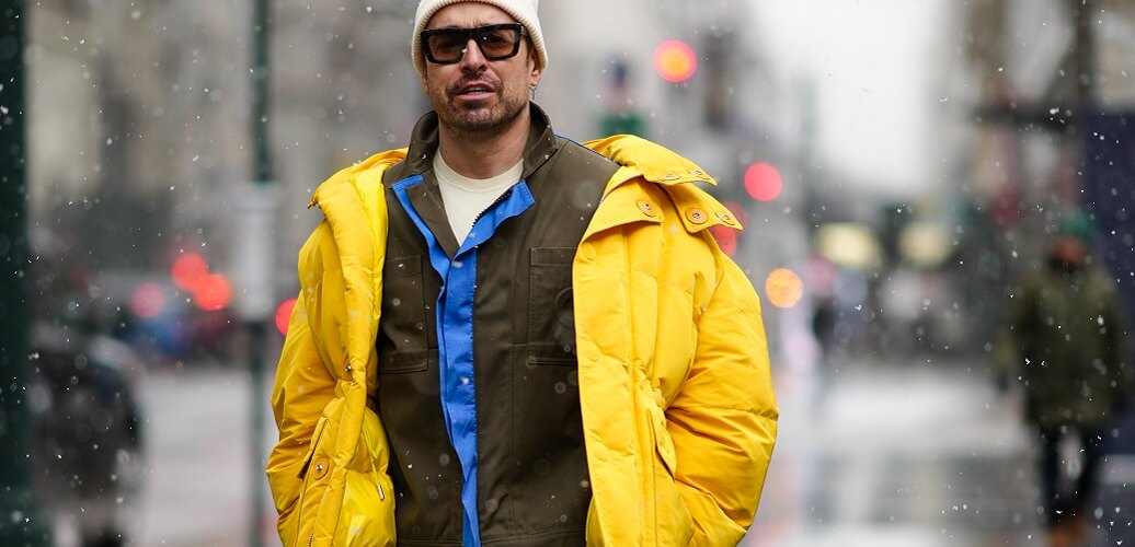 Mann in gelber Winterjacke im Schneetreiben