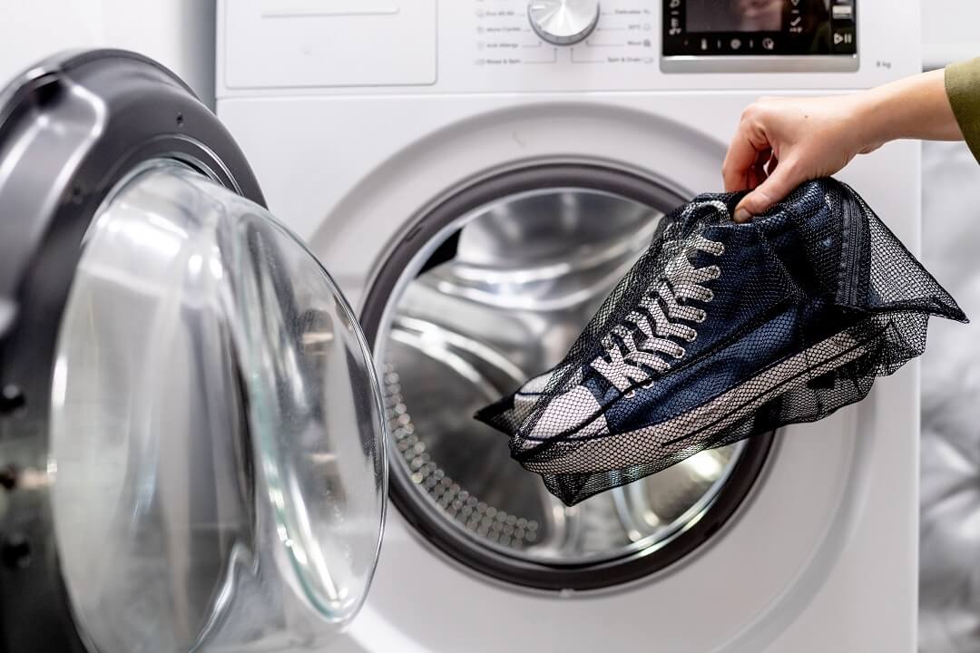 Schuhe im Wäschenetz in die Waschmaschine geben